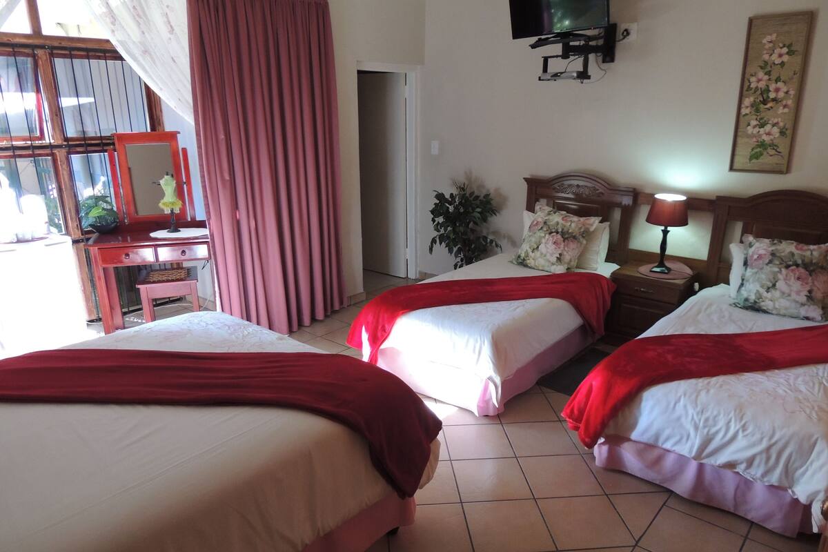 Ein Hotelzimmer mit zwei Betten, einem Schreibtisch, einem Stuhl, einem Fernseher und einem Fenster mit Vorhängen.