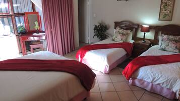Habitación de hotel con dos camas, un escritorio, una silla, un televisor y una ventana con cortinas.