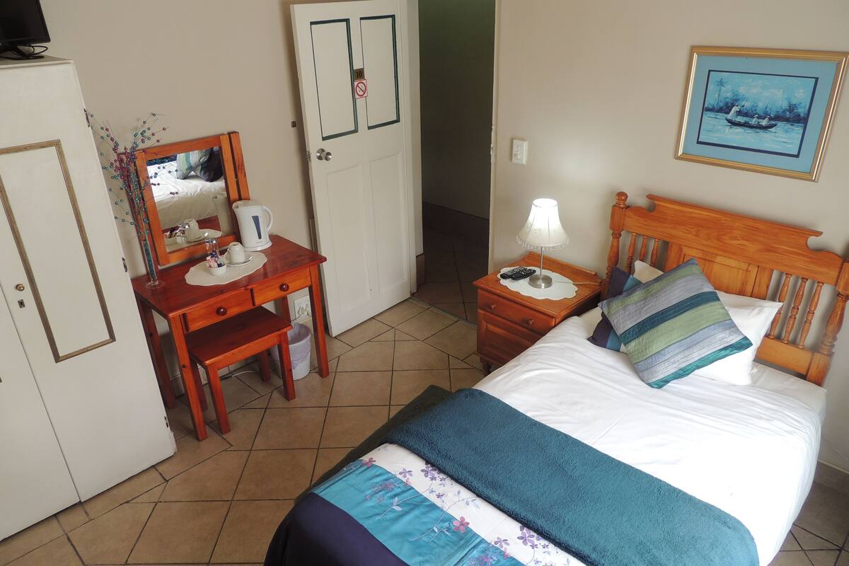 Ein Hotelzimmer mit Bett, Schreibtisch, Stuhl, Kleiderschrank und einer Tür.