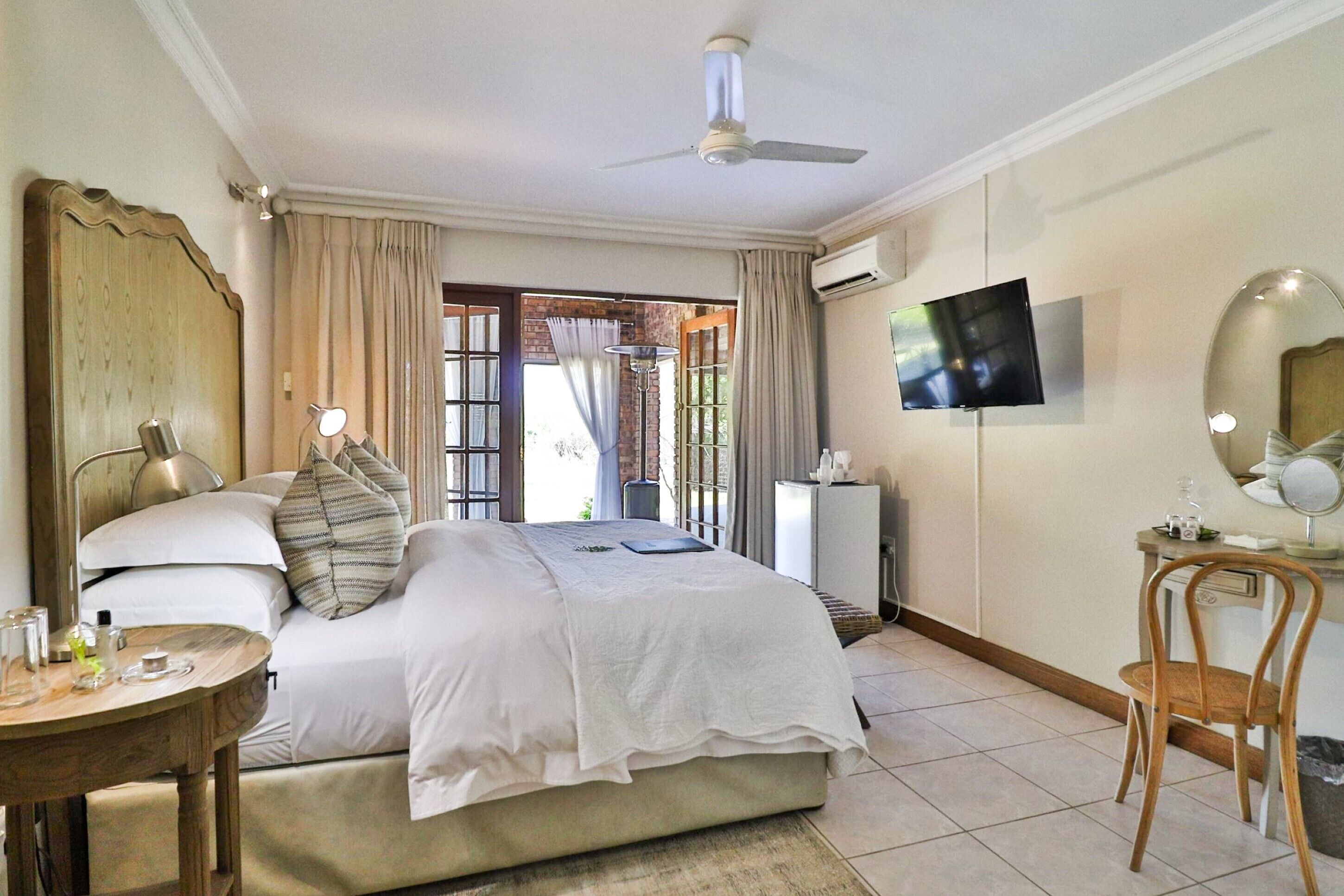 Una habitación de hotel con cama, mesita de noche, lámpara, televisión y una silla.
