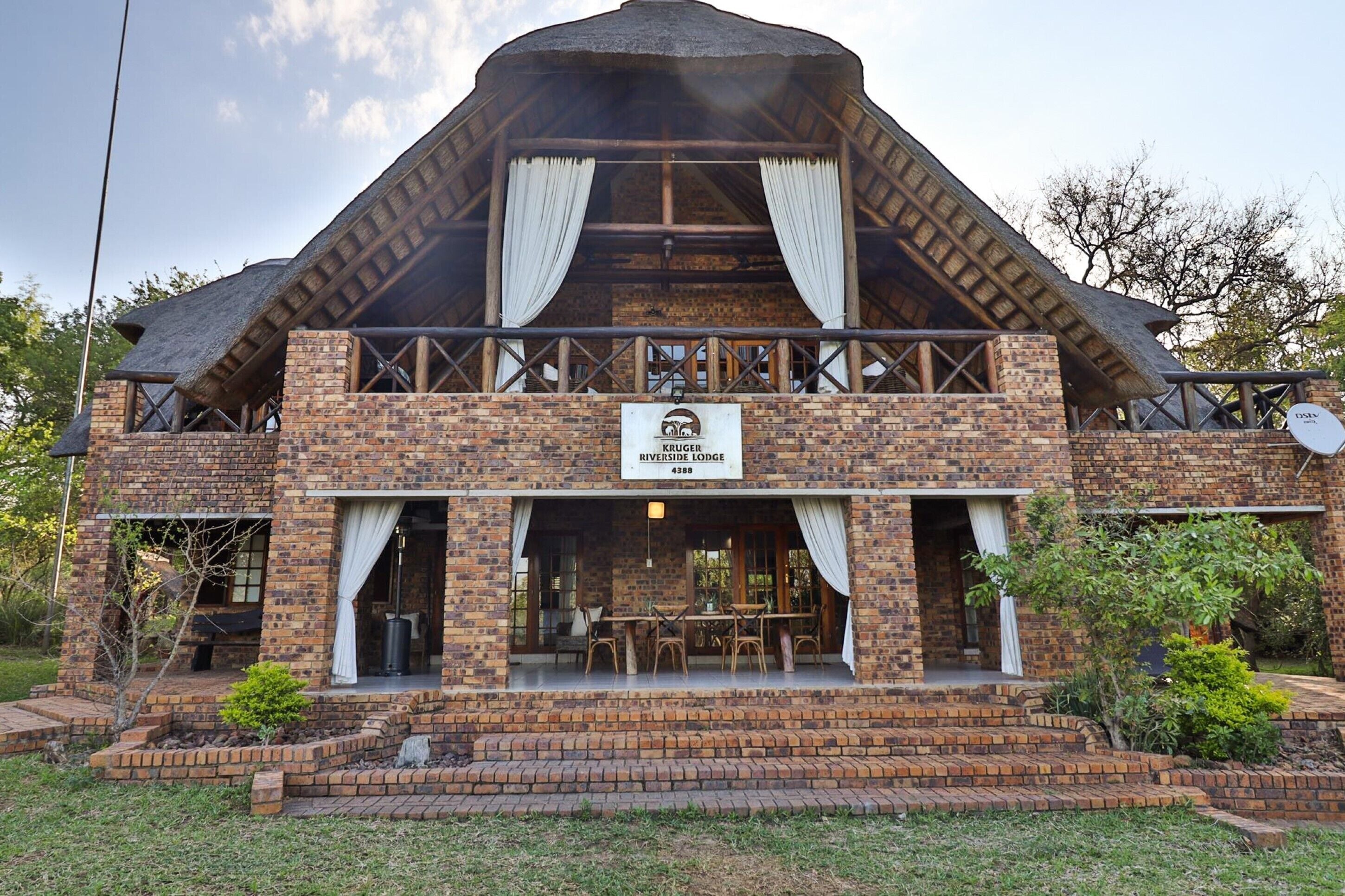A lodge with a brick facade, a thatched roof, and a sign indicating it is the Riverside Lodge.