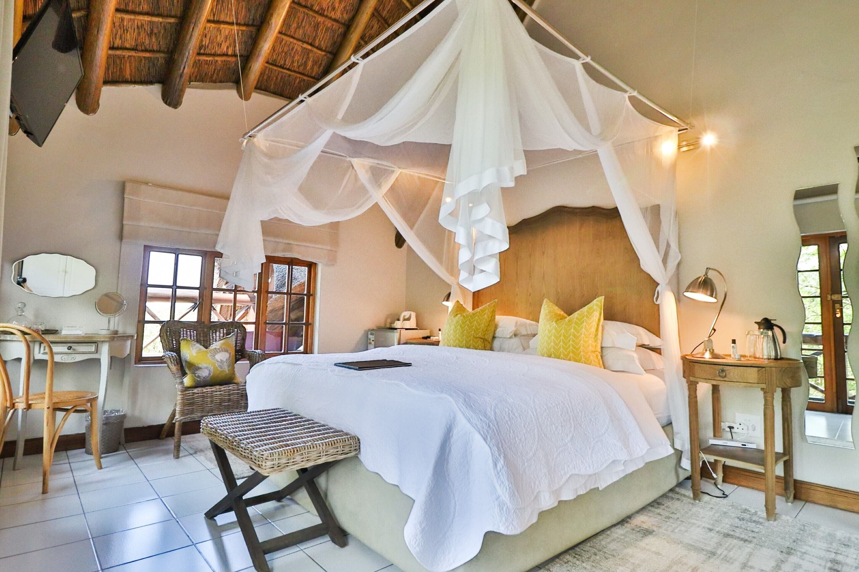 A bedroom with a four-poster bed, a desk, and a chair.