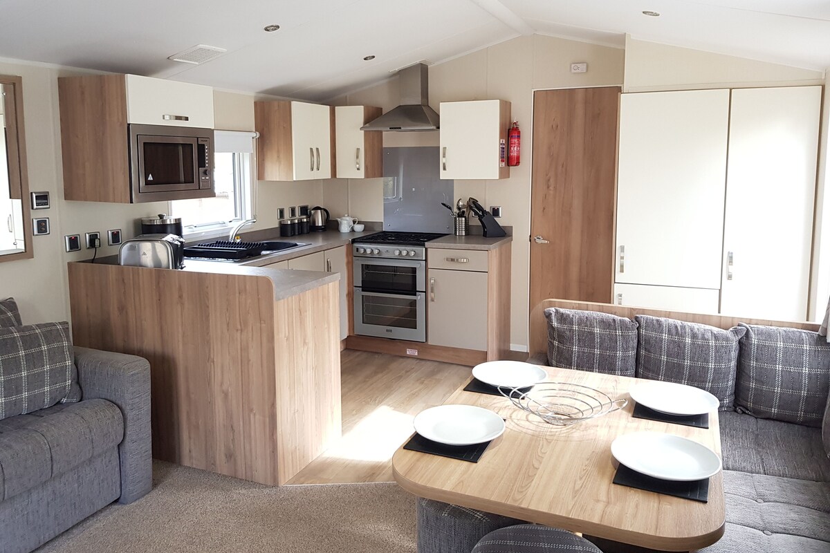 A compact kitchen with a central island, built-in microwave, stove, oven, and a small dining area with a table and chairs.