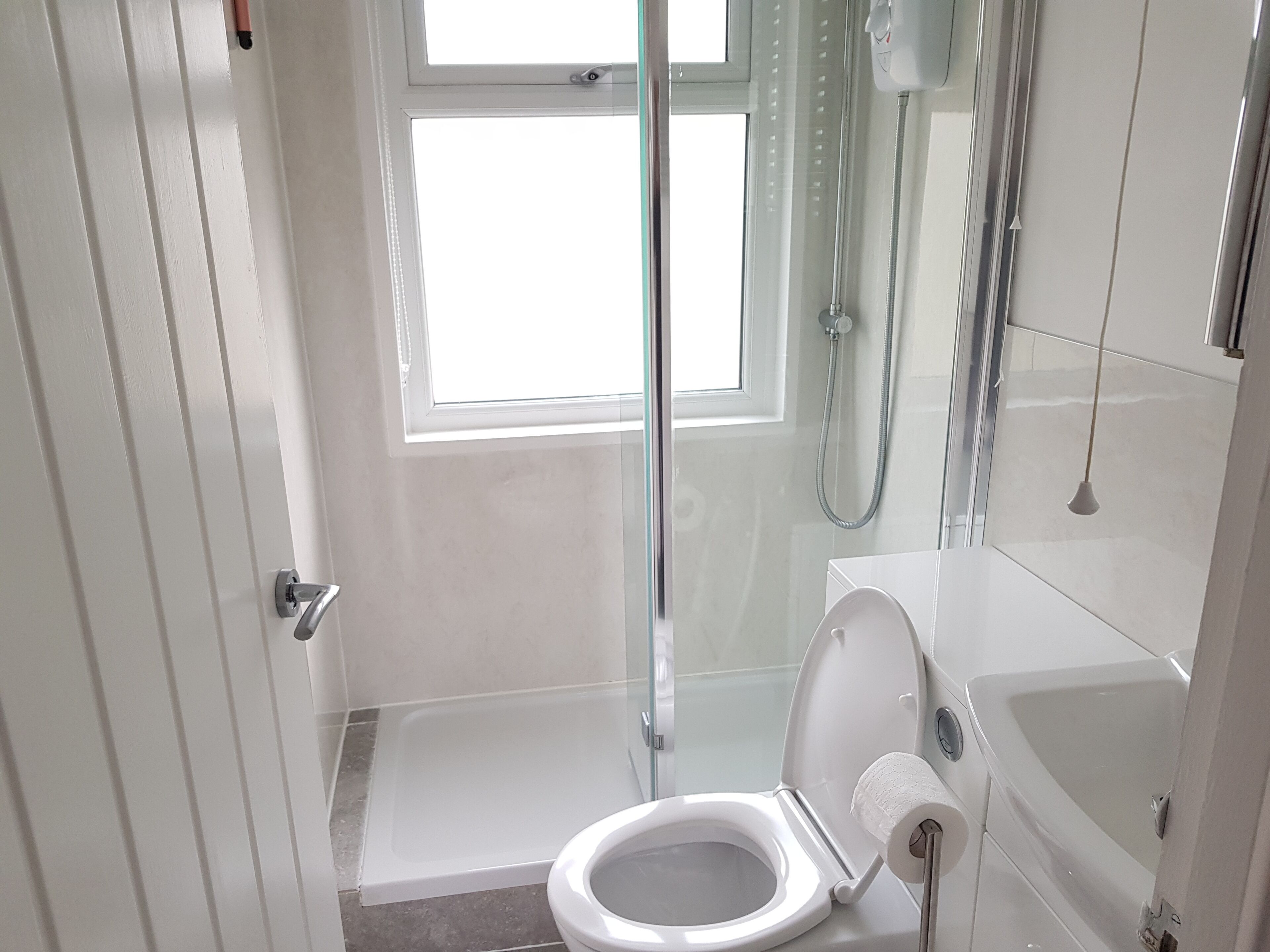 A modern bathroom with a glass shower enclosure, a toilet, and a bathtub.