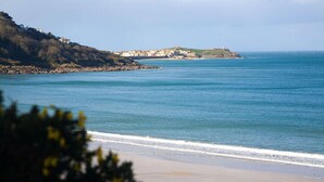 A coastal view with a beach, a rocky shoreline, and buildings on a hill. - St Ives Holiday Village (St Ives)
