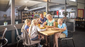 A family dining at a restaurant with a casual setting, featuring a wooden table and wicker chairs. - St Ives Holiday Village (St Ives)