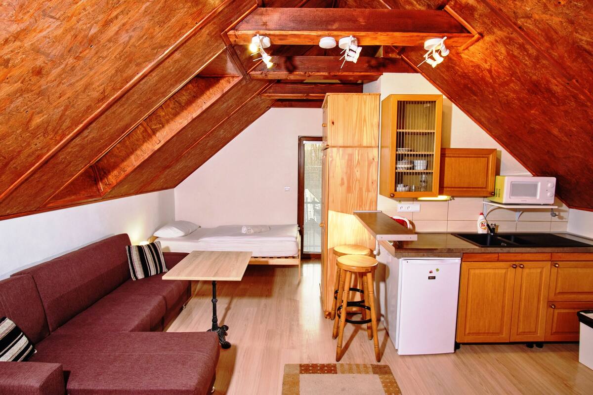 Een compact interieur van hout met een kitchenette, een bank en een eethoek.