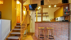 A kitchen with a wooden staircase, a brick wall, and a small bar area with stools. - Apart & Wellness Hotel VILLA IVICA  (Marianka)