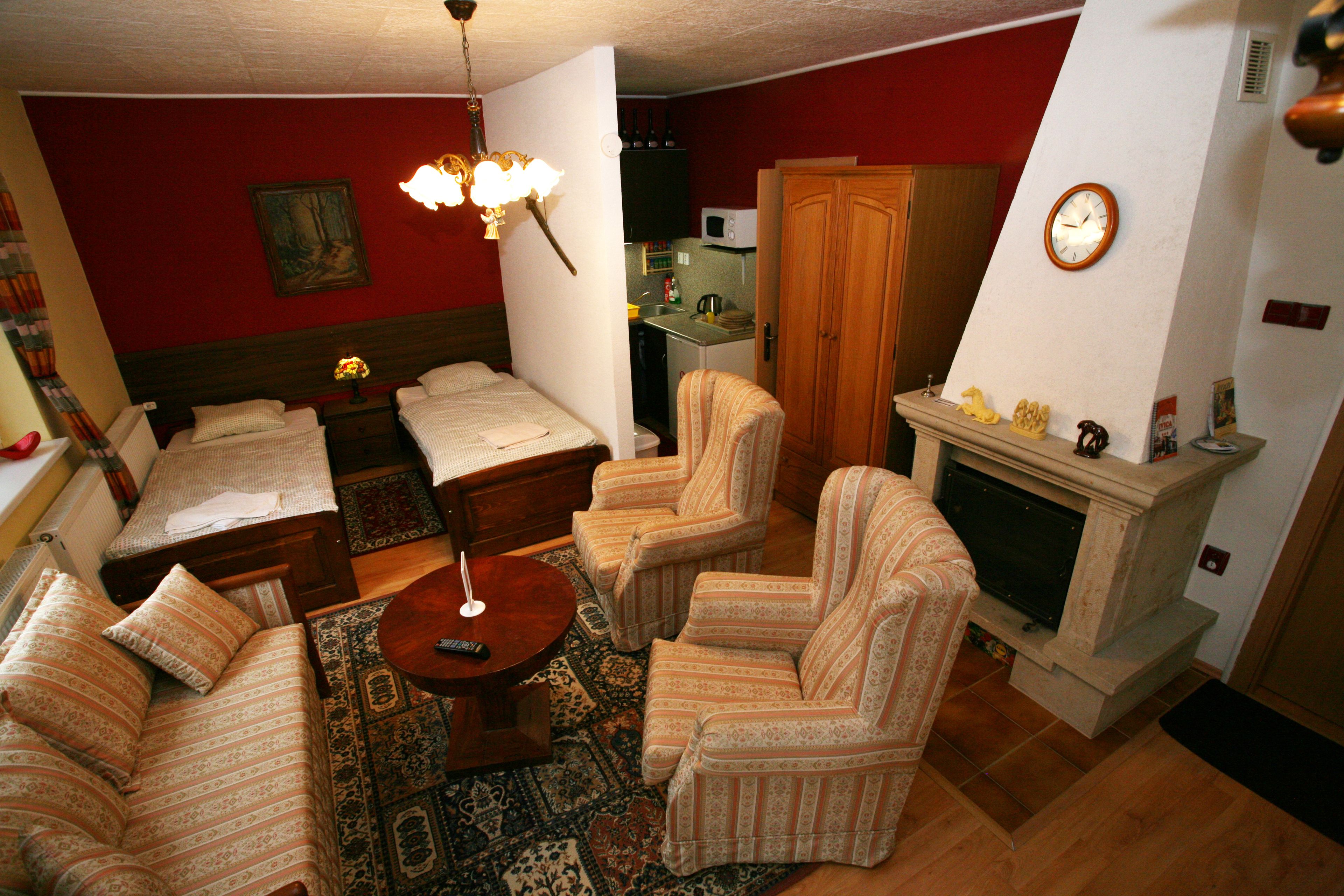 A living room with a sofa, armchairs, a coffee table, a fireplace, and a kitchen area in the background.