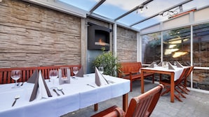 An outdoor dining area with stone walls, a built-in grill, and wooden furniture. - Apart & Wellness Hotel VILLA IVICA  (Marianka)