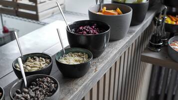 A buffet with various food items in bowls, including fruits and nuts.