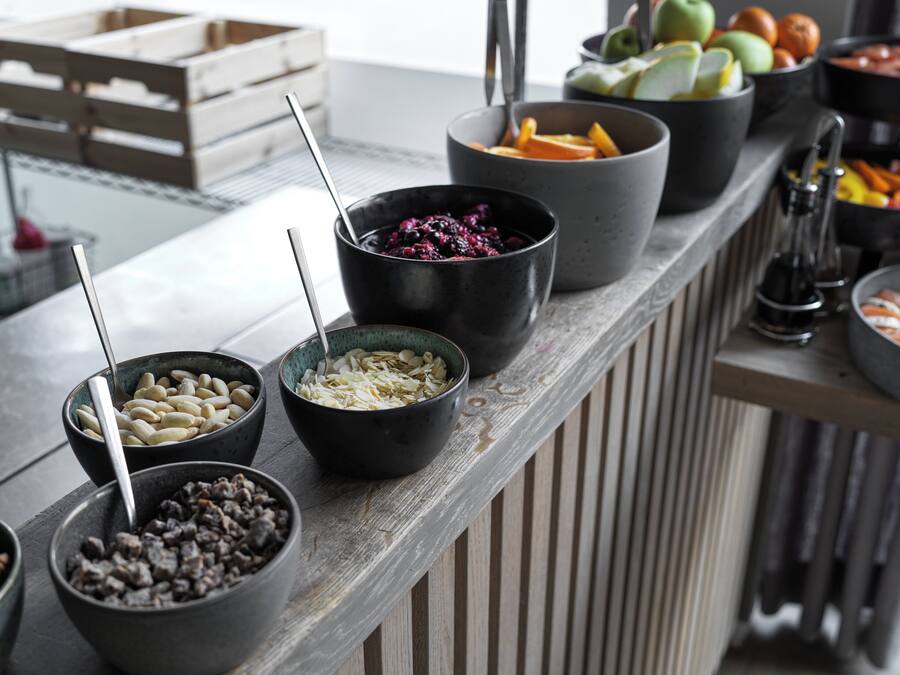 A buffet with various food items in bowls, including fruits and nuts.