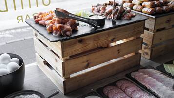 A food display with various meats and pastries on wooden crates.
