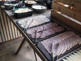 Una mesa de buffet con distintos tipos de comida, incluyendo carnes frías y quesos.