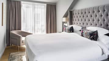 Una habitación de hotel moderna con una cama grande, una silla y una ventana con cortinas.