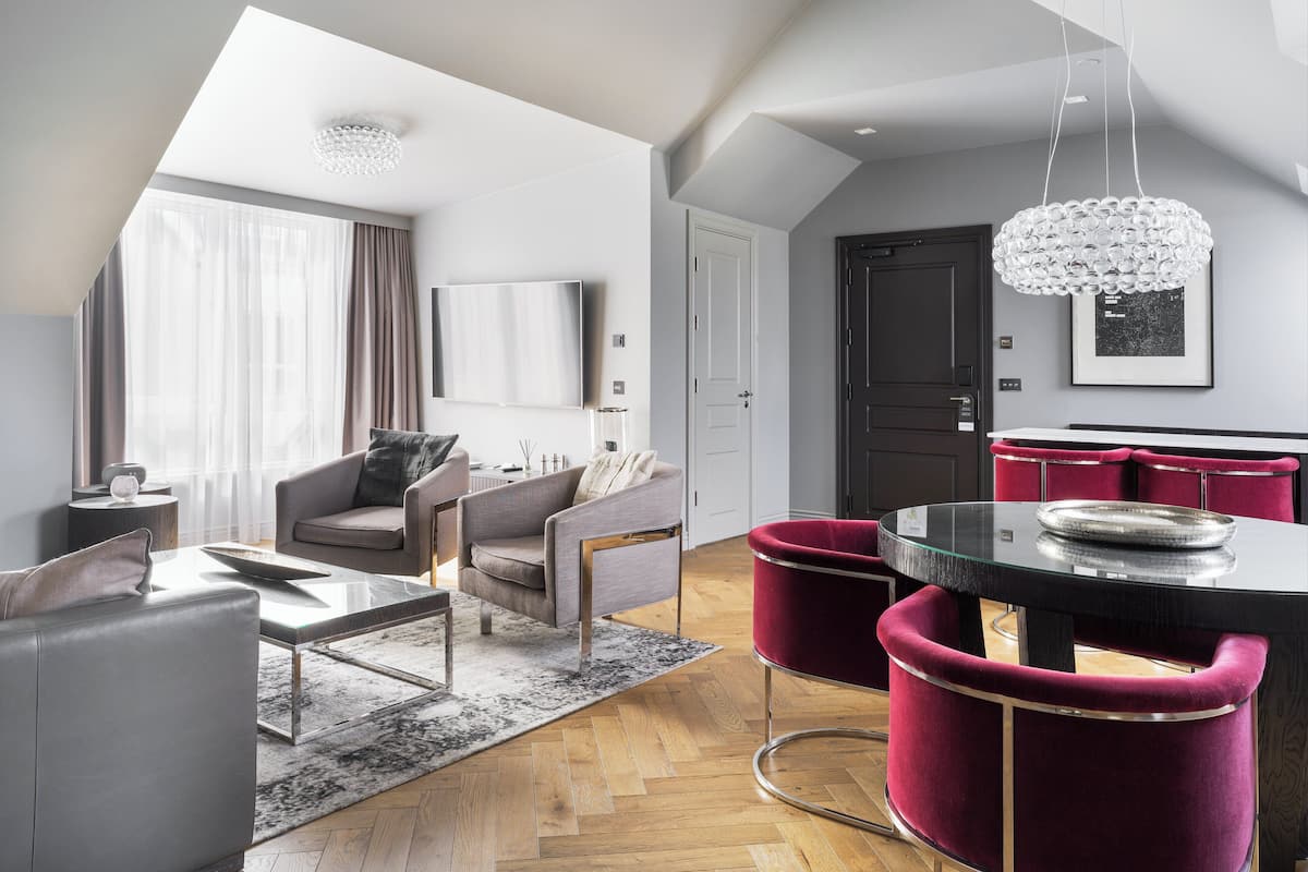 Una sala de estar moderna con un sofá, sillones, una mesa de centro y un comedor con una mesa y sillas.