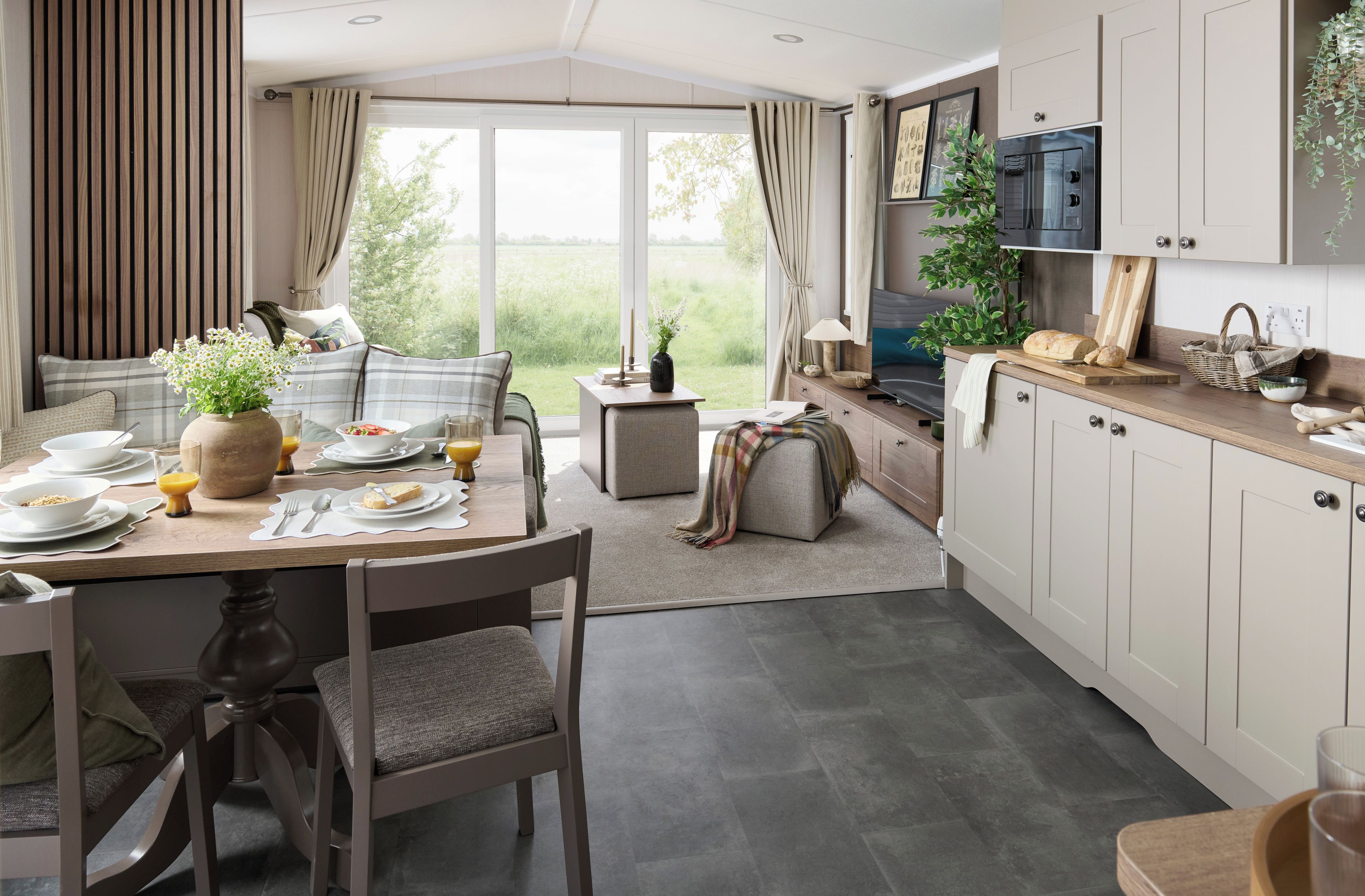 Une cuisine moderne avec un coin repas, de grandes fenêtres et une vue sur la verdure.