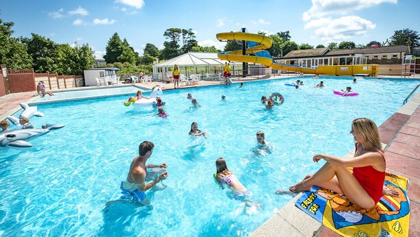 Una piscina con varias pistas de natación, un tobogán de agua y juguetes inflables.