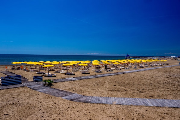 On the beach, sun-loungers, beach umbrellas, windsurfing