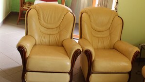 Una habitación con dos sillones de cuero, una silla de madera, una mesita y una puerta que da a otra estancia.
