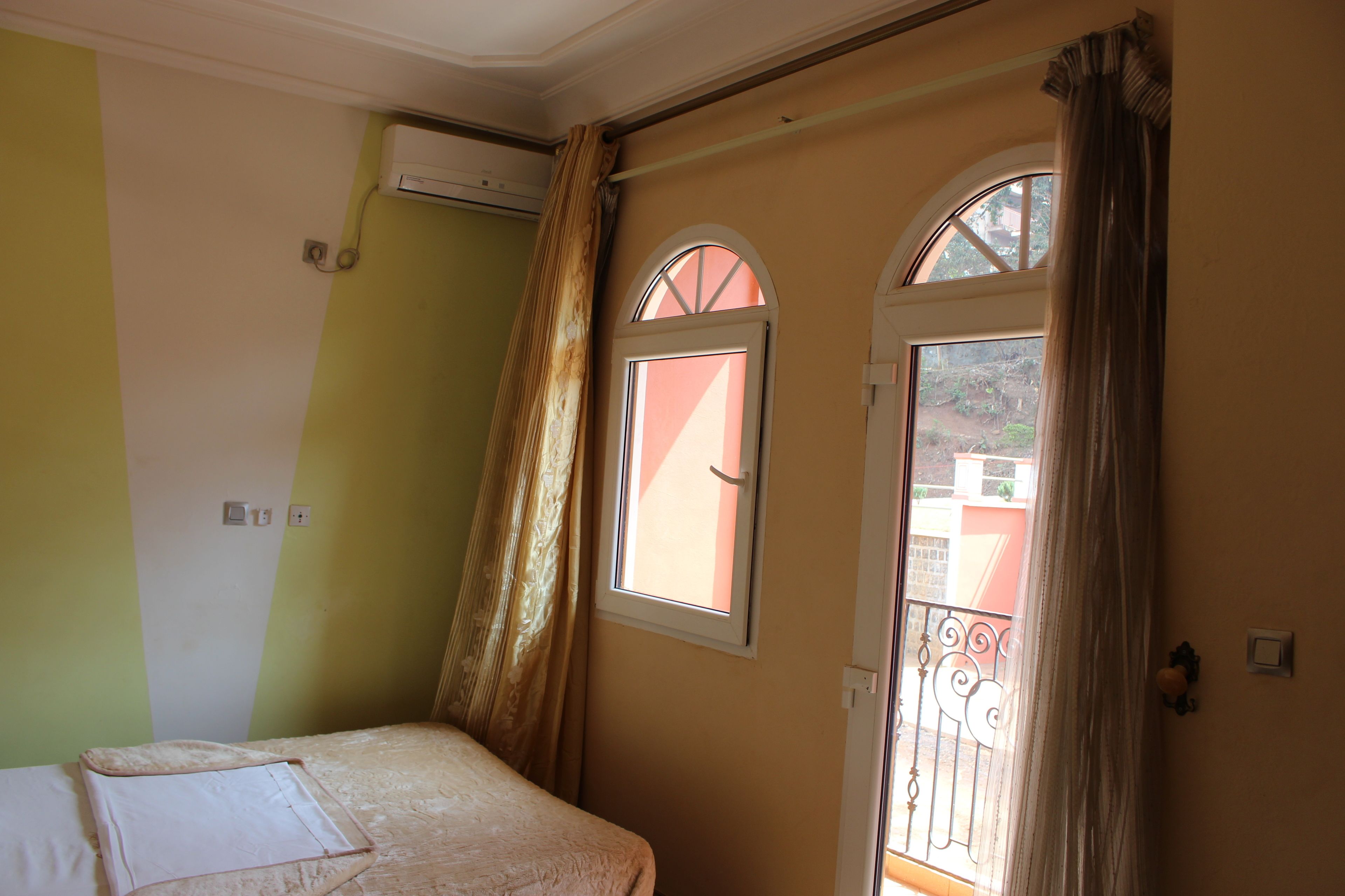 A bedroom with a bed, a window, and a door.