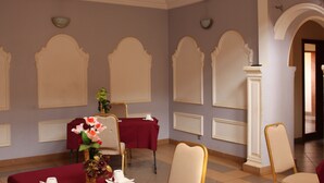 Una habitación con una mesa roja, sillas color beige y un jarrón de flores.
