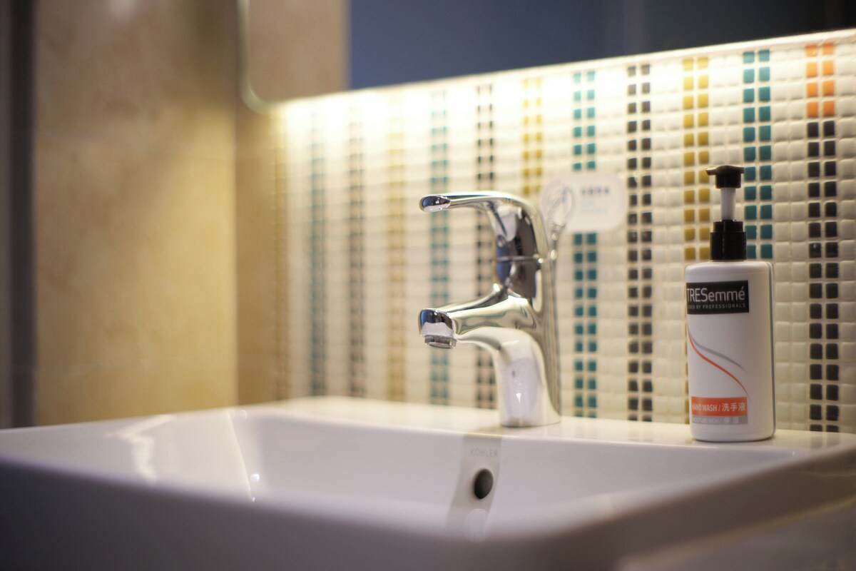 A bathroom sink with a chrome faucet and a bottle of hand wash soap.
