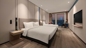 Moderni hotellihuone, jossa on kaksi sänkyä, työpöytä ja televisio.