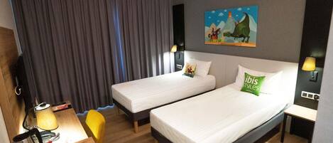 A hotel room with two beds, a desk with a lamp, a chair, and a painting on the wall.