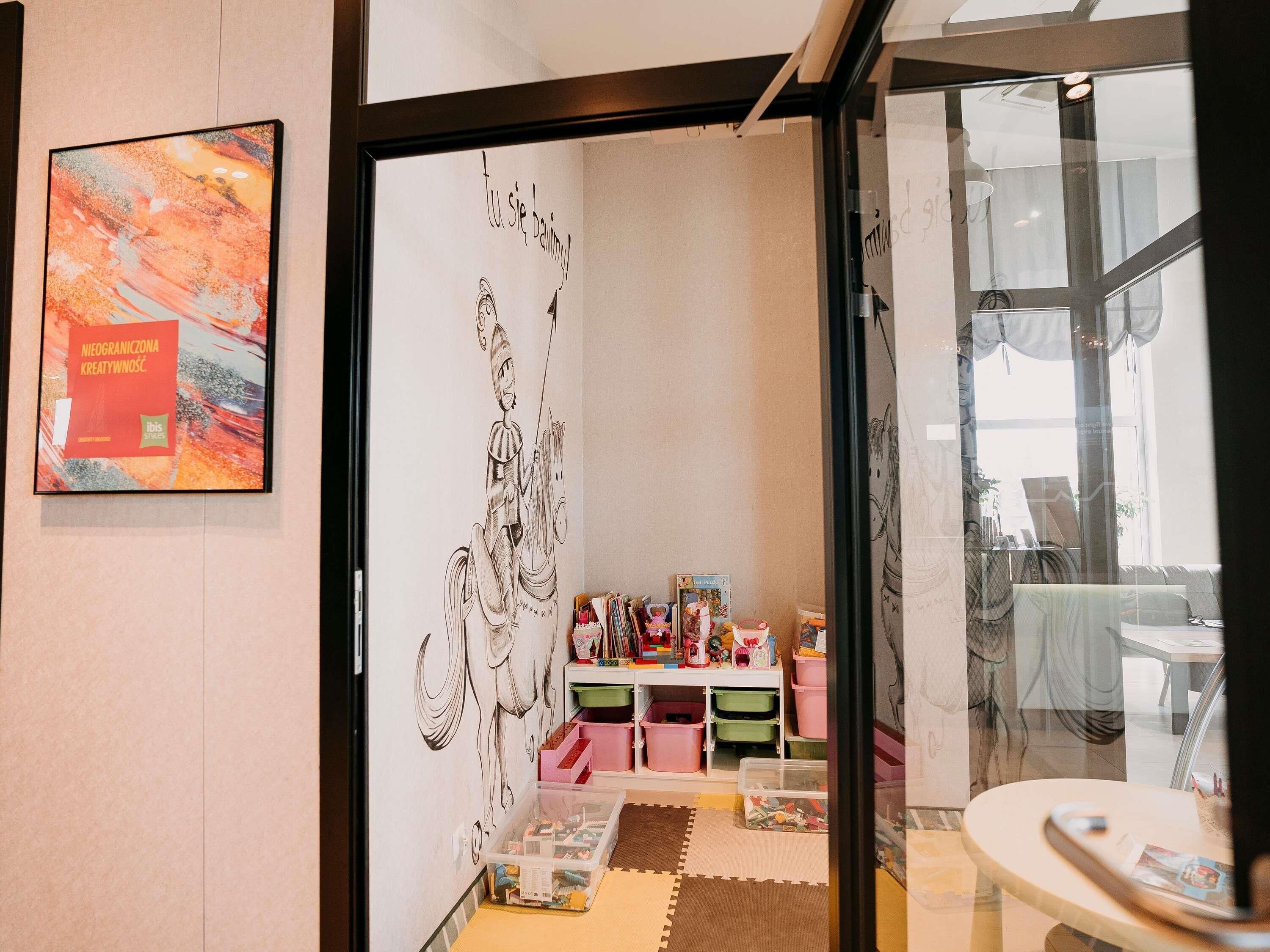 A room with a large abstract painting, a wall with a black and white drawing, and a glass door leading to another space.