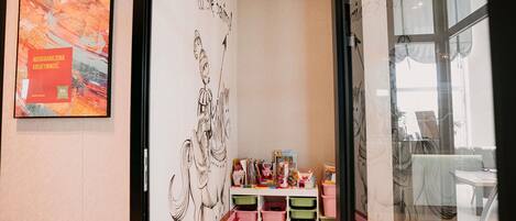 A room with a large abstract painting, a wall with a black and white drawing, and a glass door leading to another space.