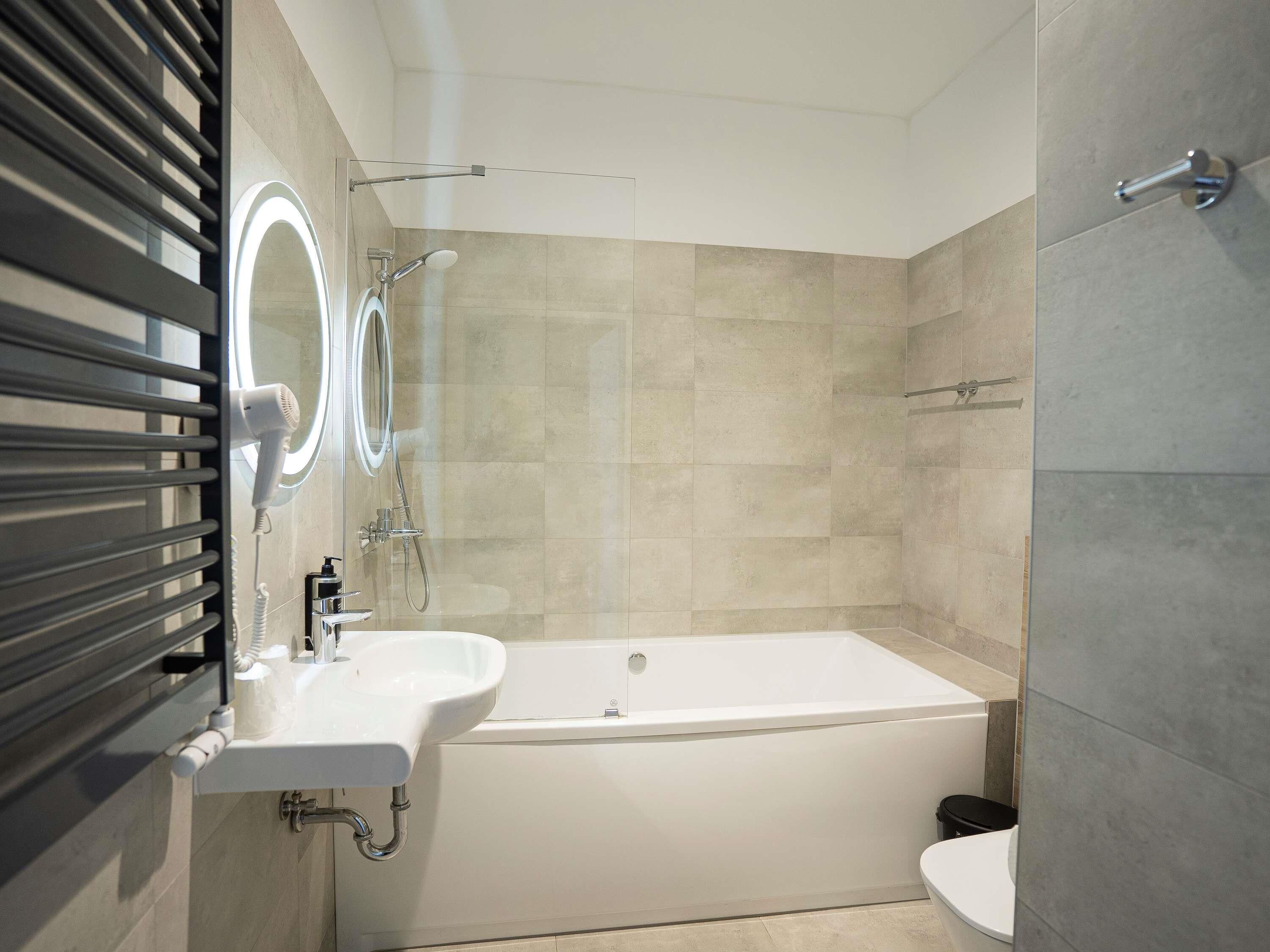 Un baño moderno con bañera, dos lavamanos, inodoro y ducha.