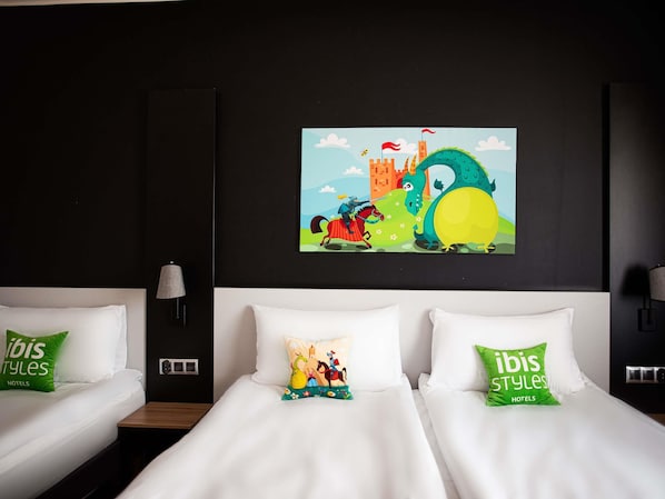 A hotel room with two beds, each with a pillow featuring the ibis styles logo. A colorful mural depicting a knight on a horse and a dragon is on the wall above the beds. - ibis styles Grudziadz (Grudziadz)