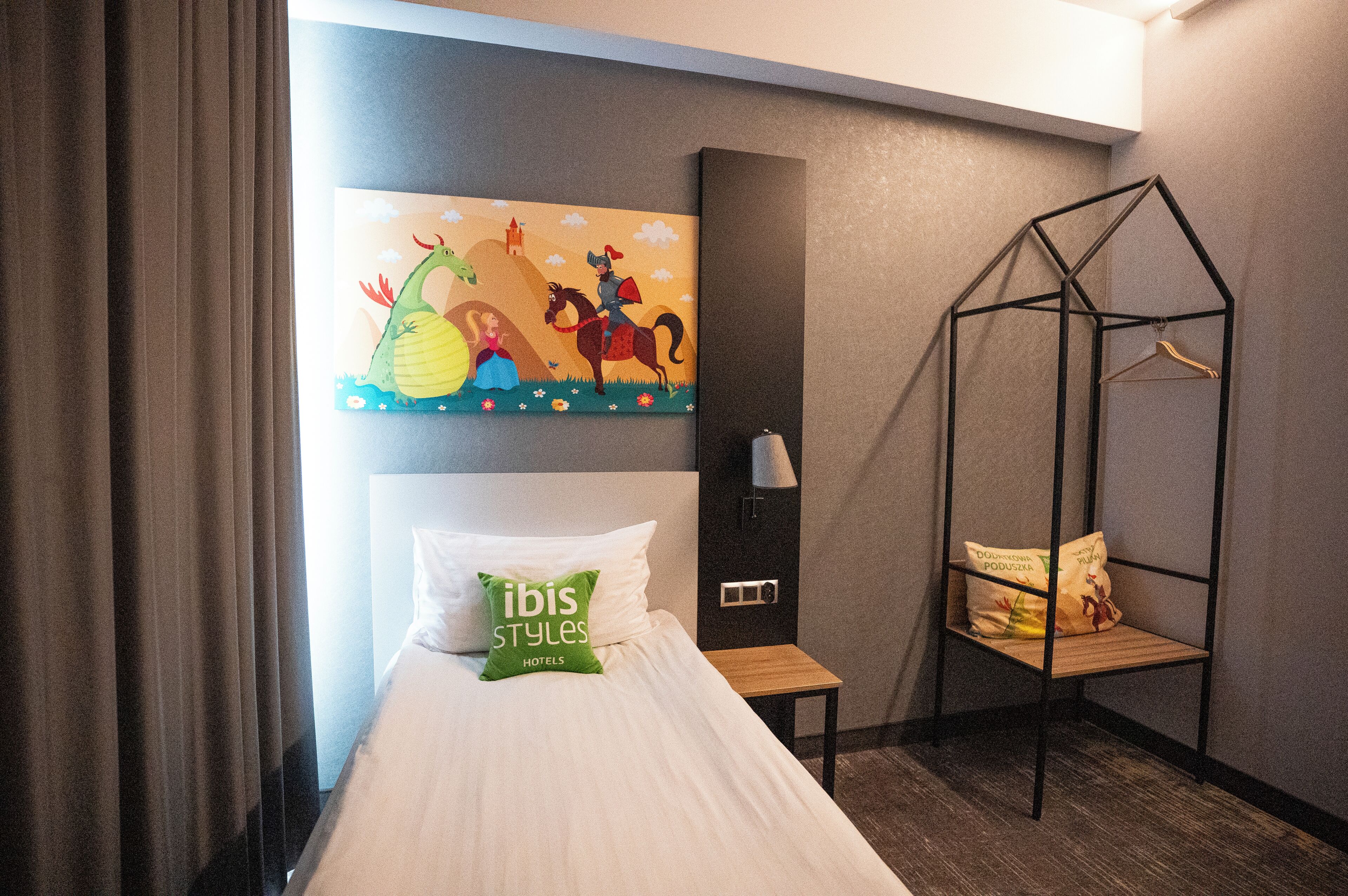 Ein Hotelzimmer mit einem Bett, einem Wandbild, einem Hängekorbstuhl und einem kleinen Tisch.