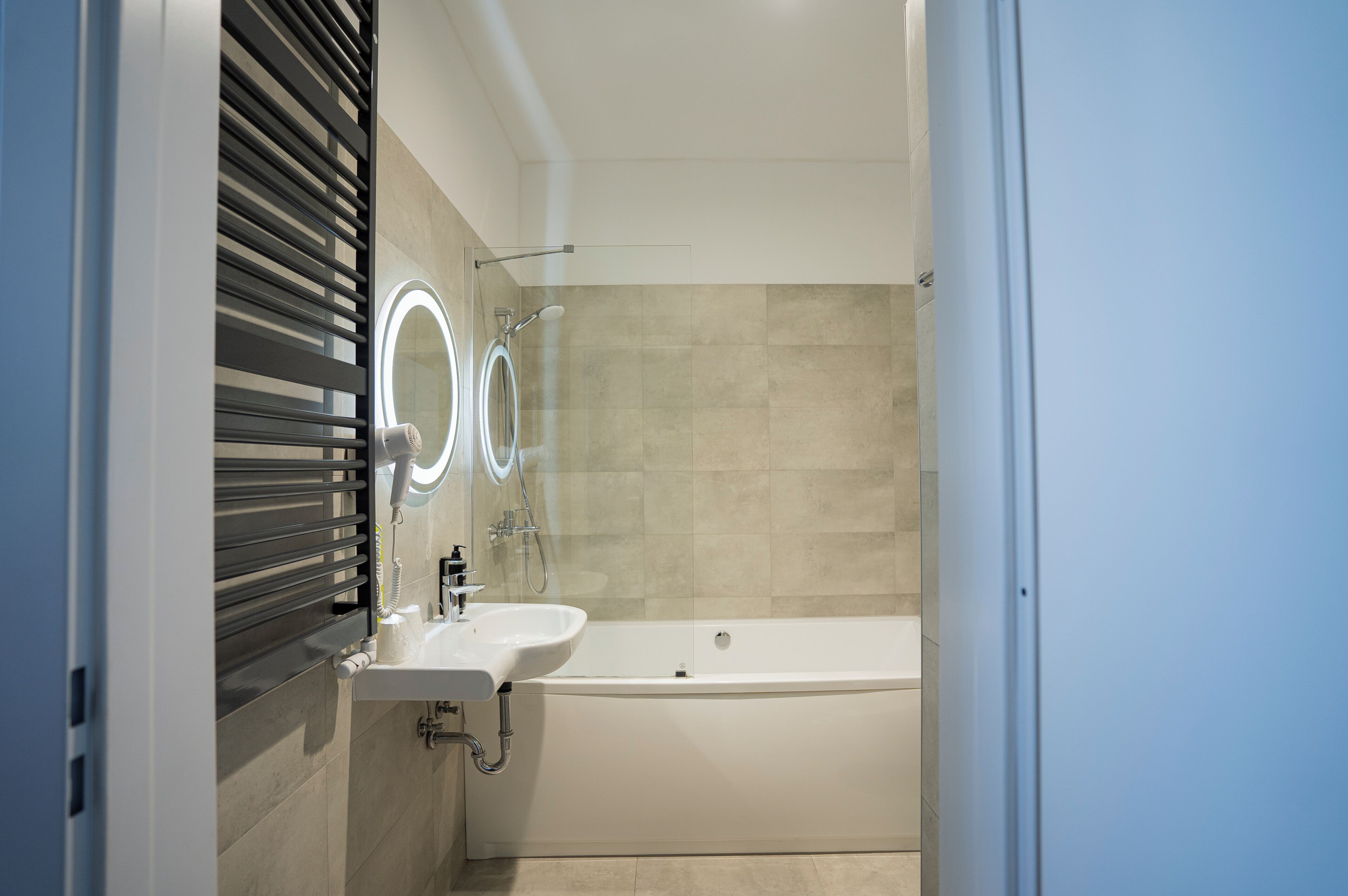 Un baño moderno con bañera, lavamanos y espejo con iluminación integrada.