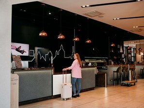 A hotel reception area with a modern design, a reception desk, a seating area, and a bar.
