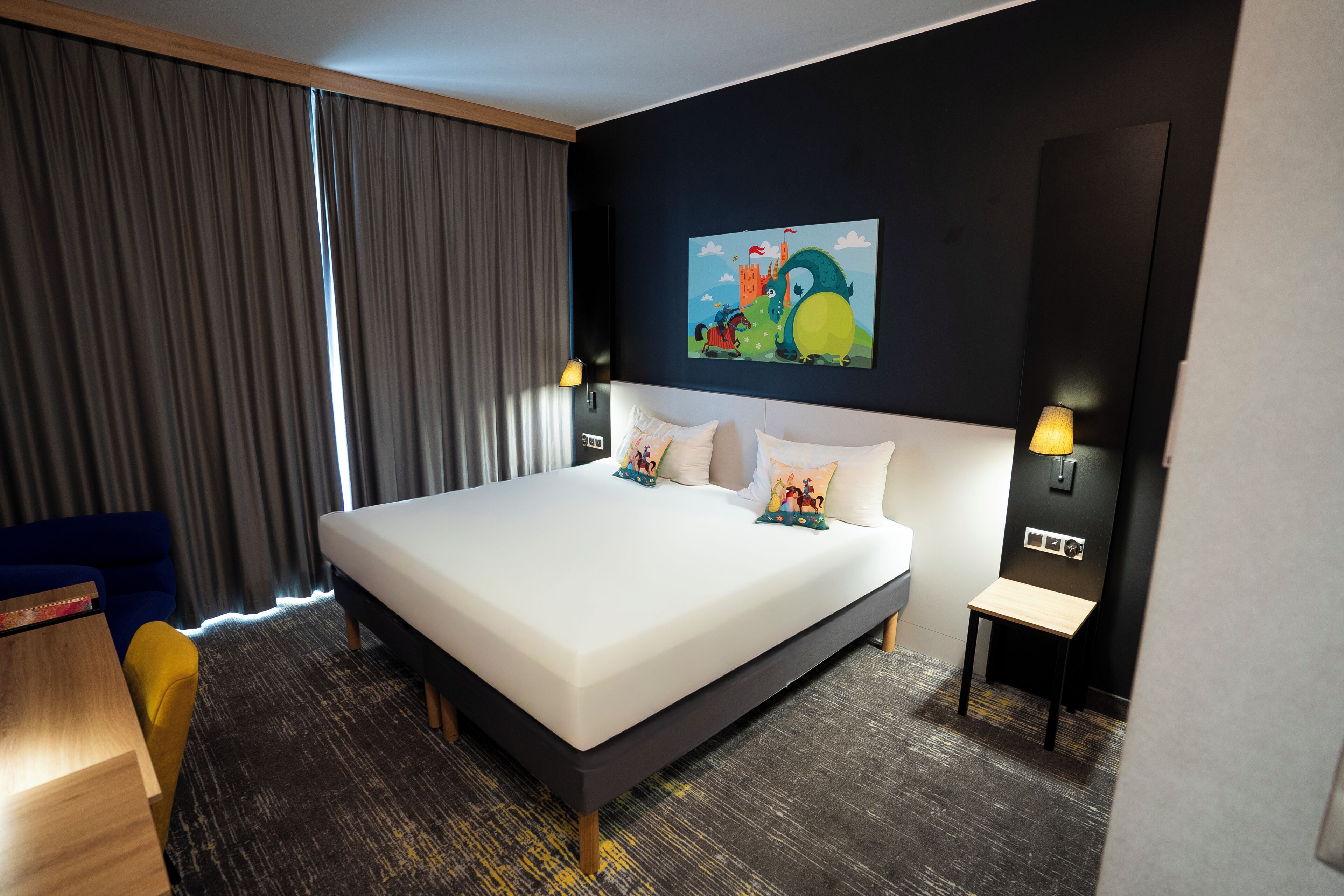 Ein Hotelzimmer mit einem großen Bett, einem Schreibtisch, einem Stuhl und einem Gemälde an der Wand.