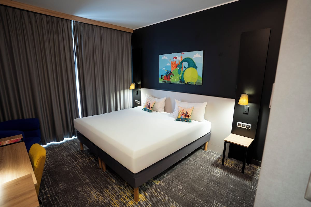 Une chambre dâhĂŽtel avec un grand lit, un bureau, une chaise et un tableau au mur.