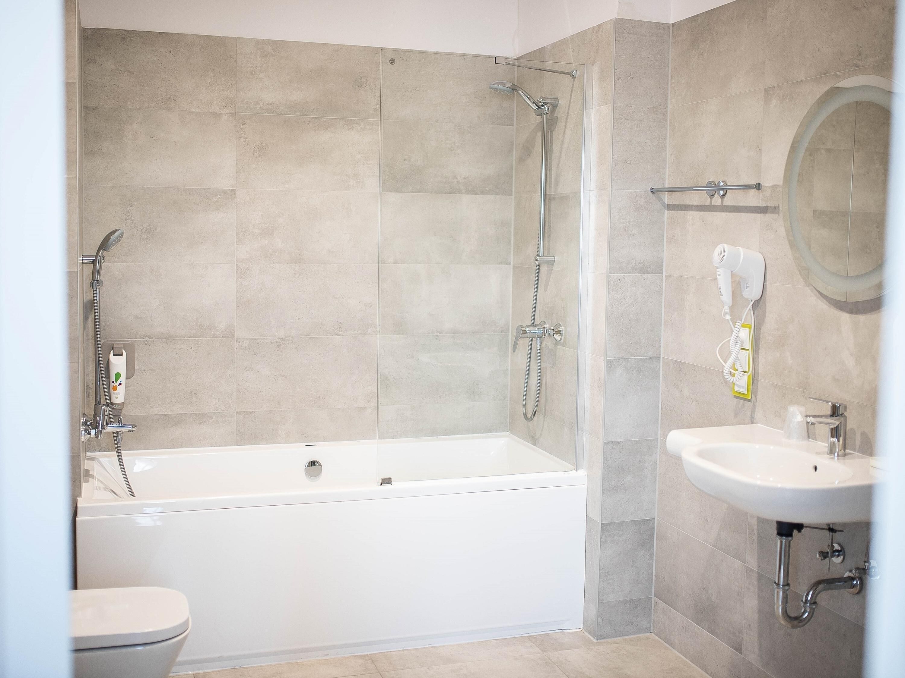 A modern bathroom with a bathtub, shower, toilet, and sink.