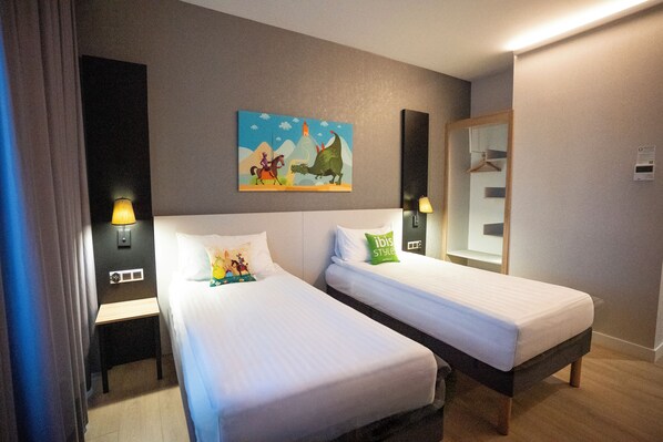 Habitación de hotel con dos camas, un cuadro en la pared, un espejo y dos lámparas de noche.