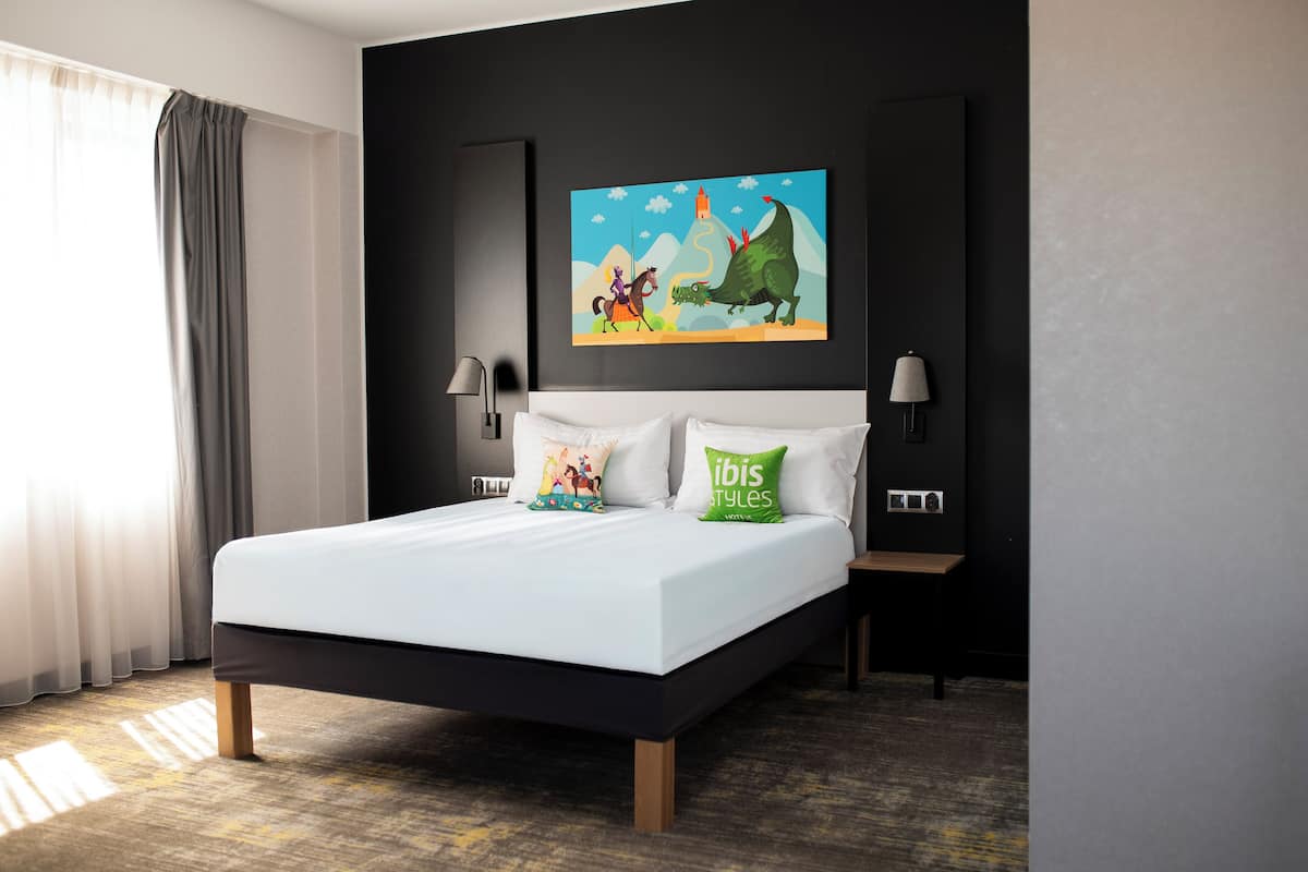 Une chambre dâhĂŽtel moderne avec un grand lit, deux lampes de chevet, un tableau accrochĂ© au mur et une vue sur lâextĂ©rieur.