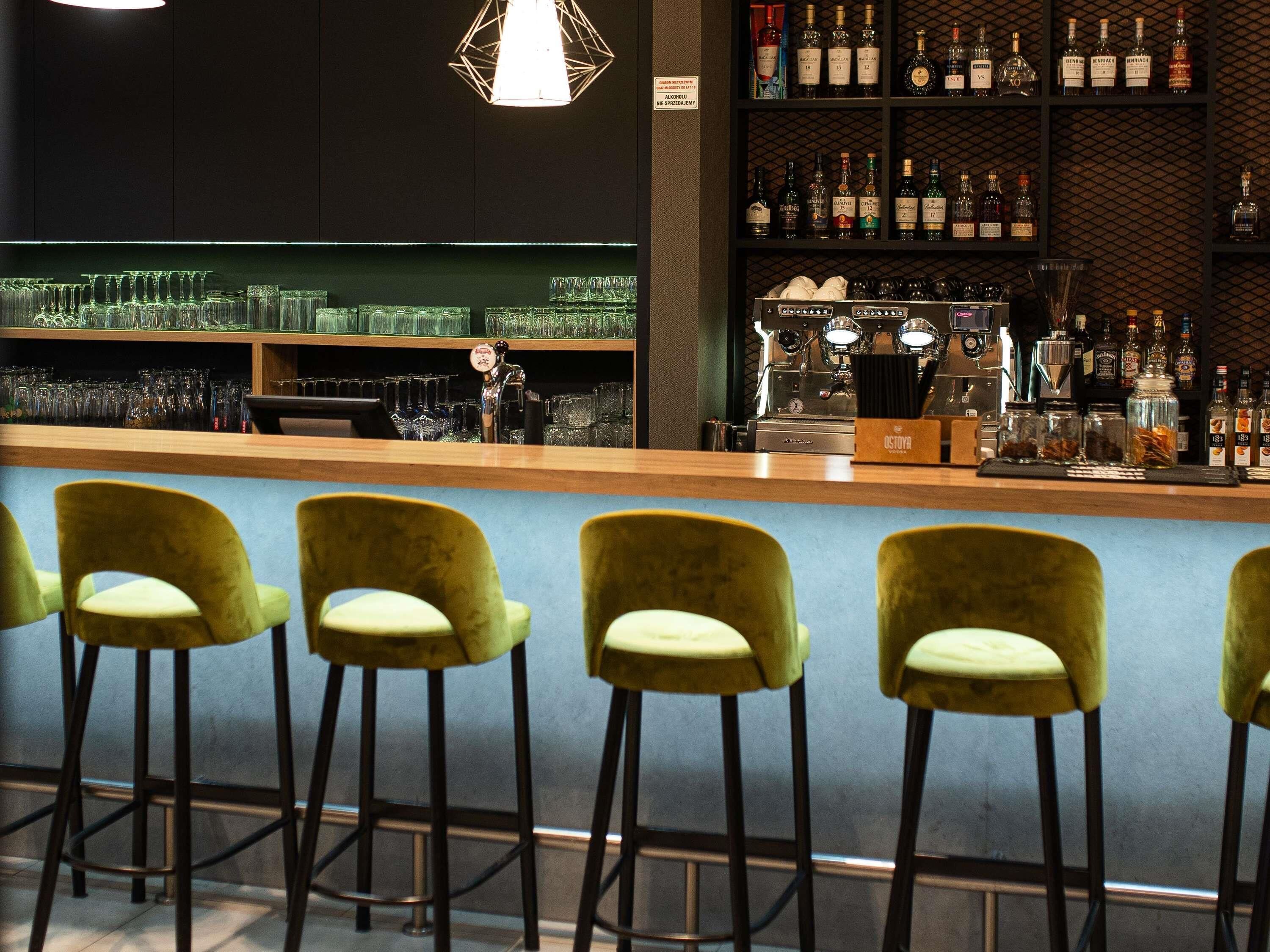 A bar area with stools, a bar counter, and shelves of liquor bottles.