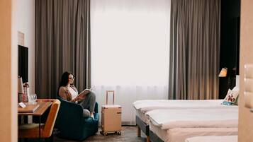 Una habitación de hotel con cama, escritorio, silla, maleta y televisor.