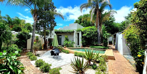 Una piscina al aire libre, sombrillas, sillones reclinables de piscina