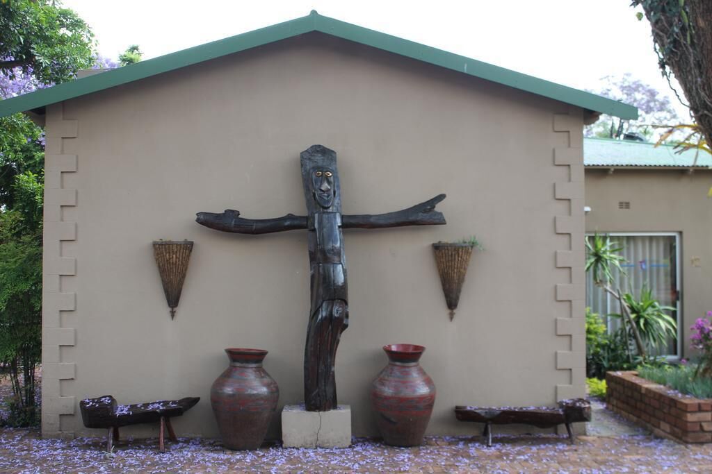 Un bâtiment orné d’une sculpture en forme de croix, de deux vases et de deux bancs.