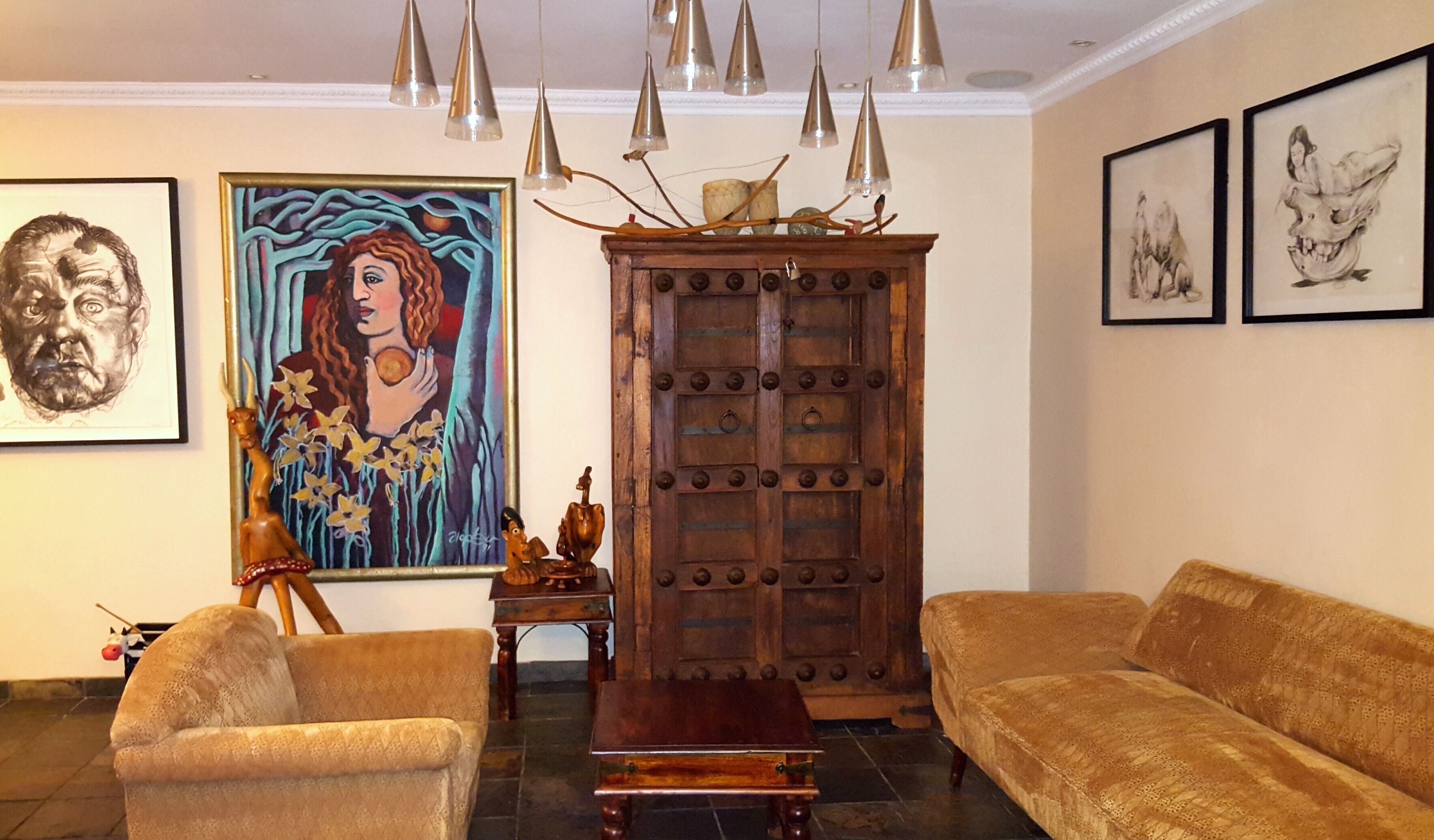 A living room with a sofa, a wooden cabinet, and artwork on the walls.