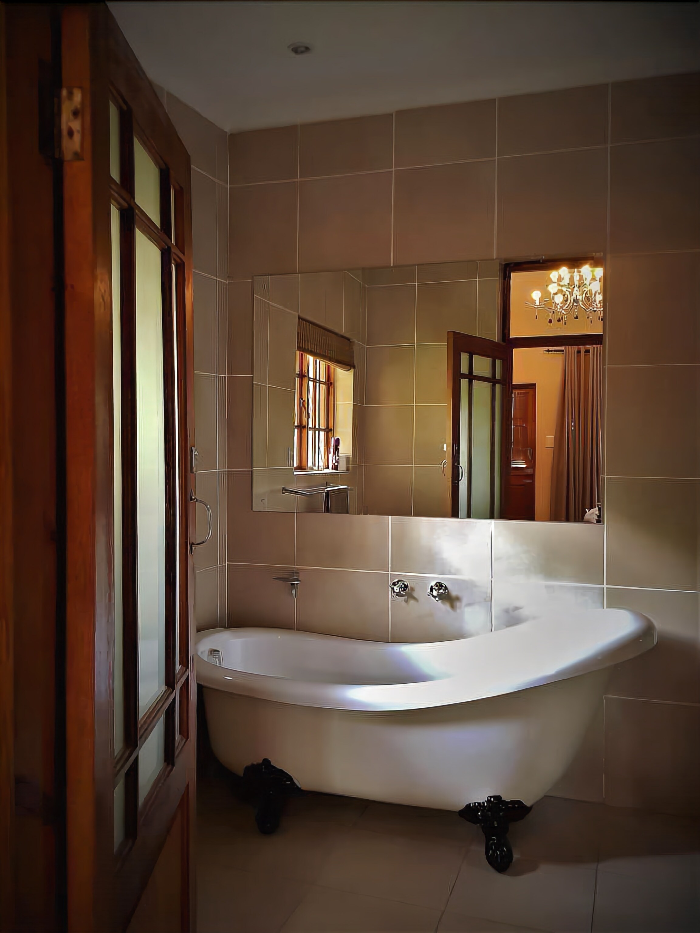 Un bagno con una vasca freestanding, uno specchio grande e un lampadario.