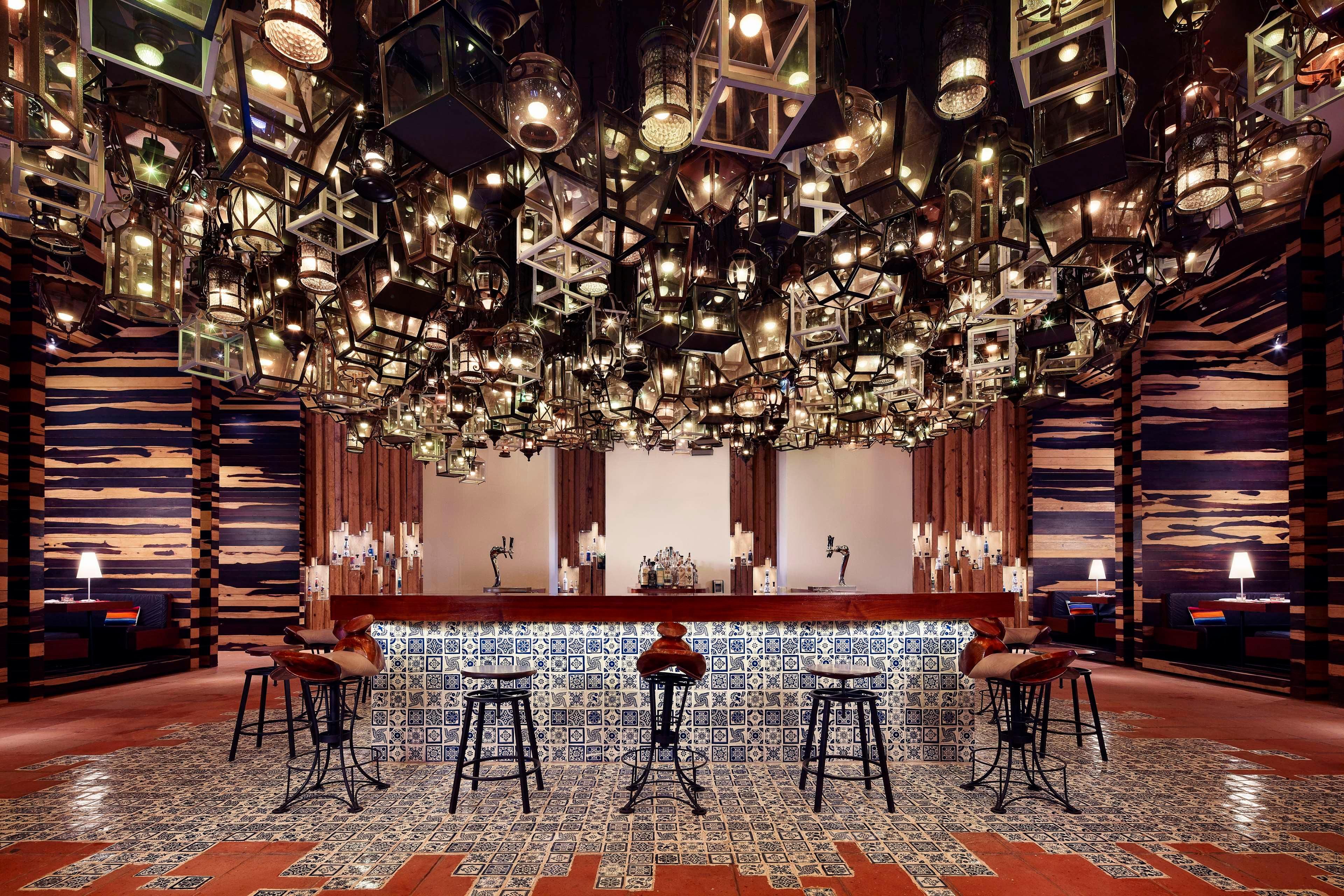 A bar area with multiple stools, a counter, and hanging light fixtures.