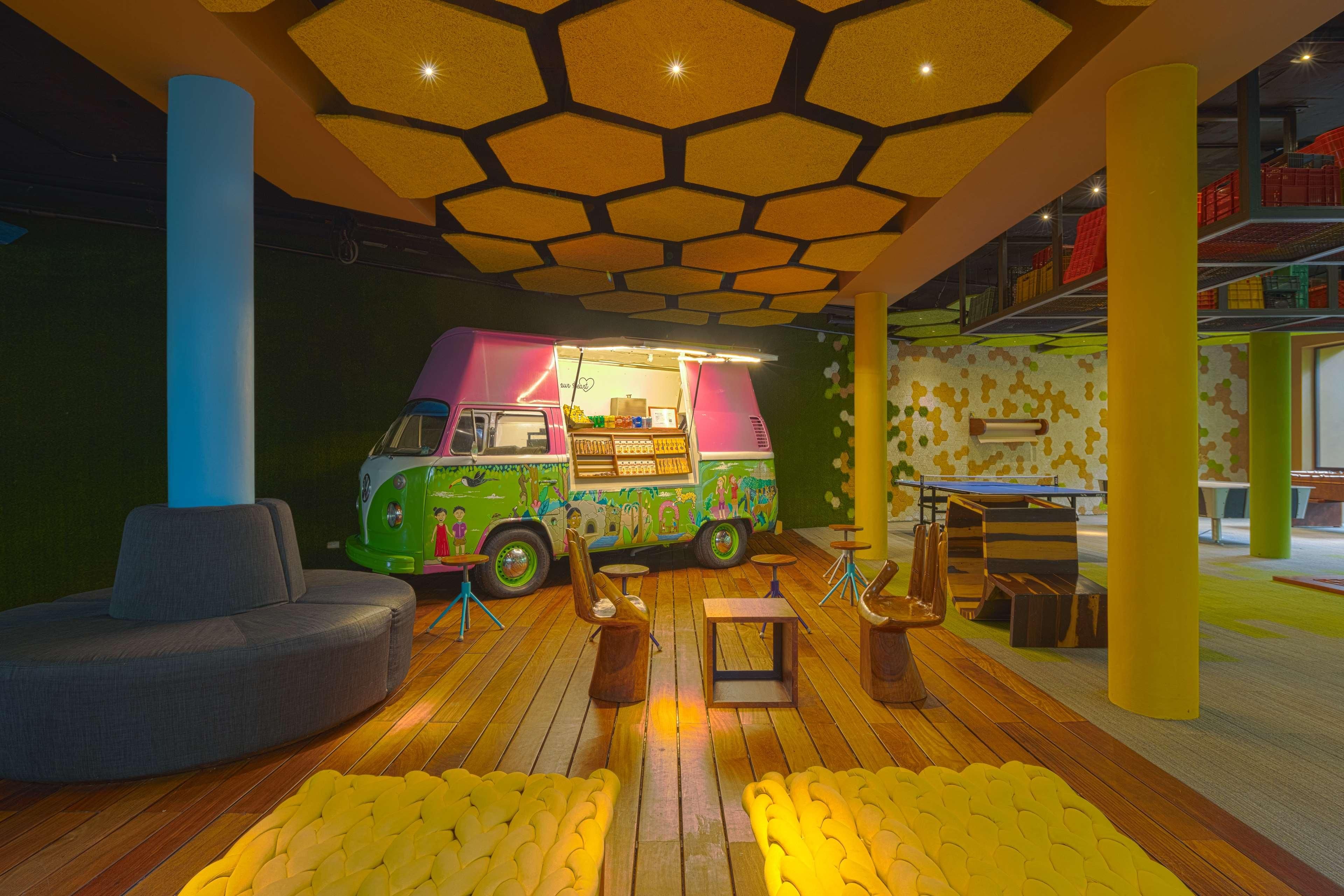 A play area with a colorful play truck, a gray sofa, and yellow bean bag chairs.
