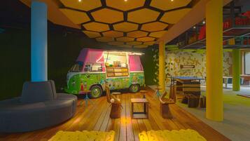 A play area with a colorful play truck, a gray sofa, and yellow bean bag chairs.